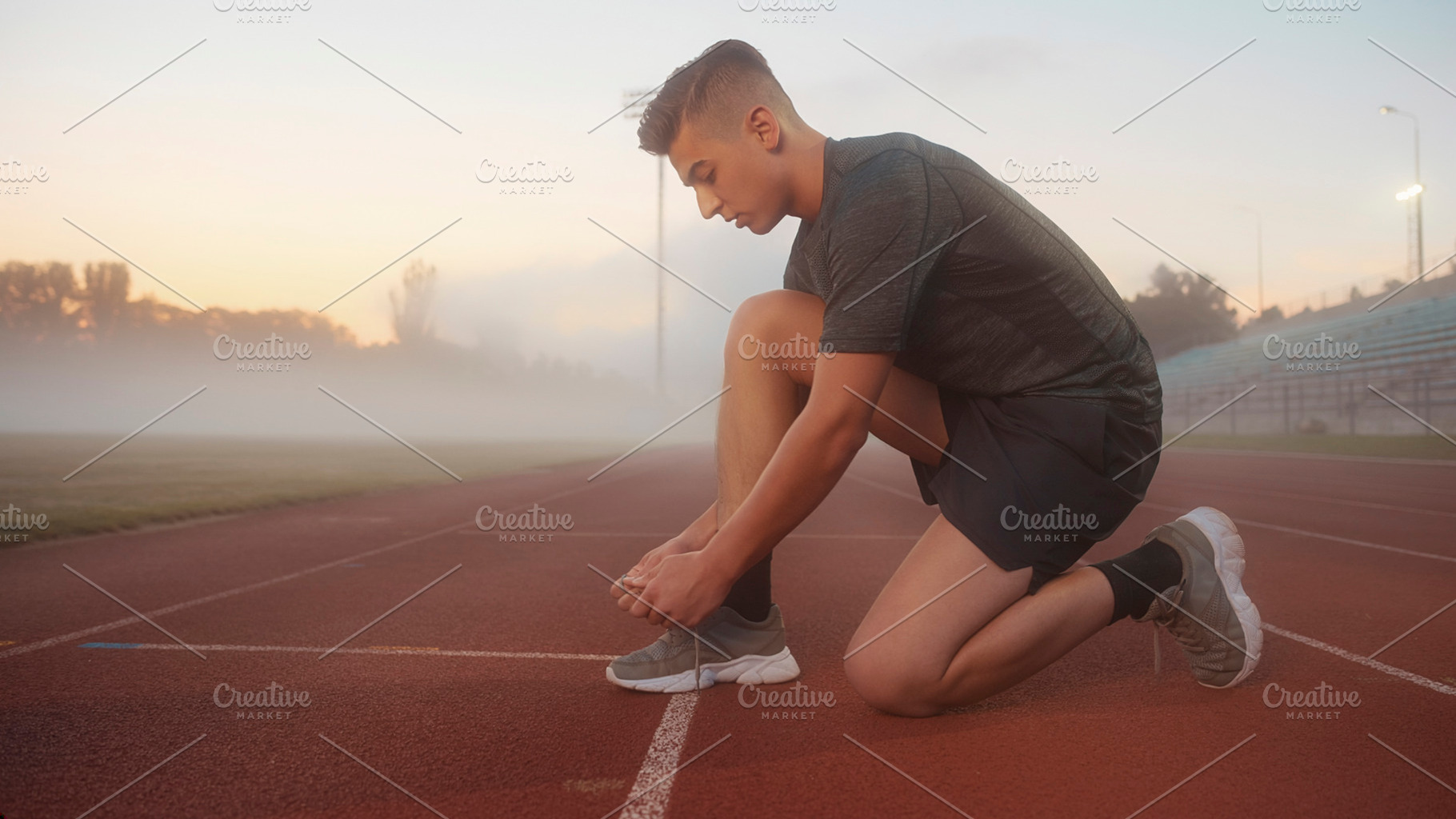 Runner tying shoe on track at foggy morning, a Photo by DanFLCreativo