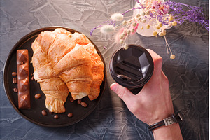 Guest holding coffee and croissants, a Food & Drink Photo by Stockphoto by vzwer
