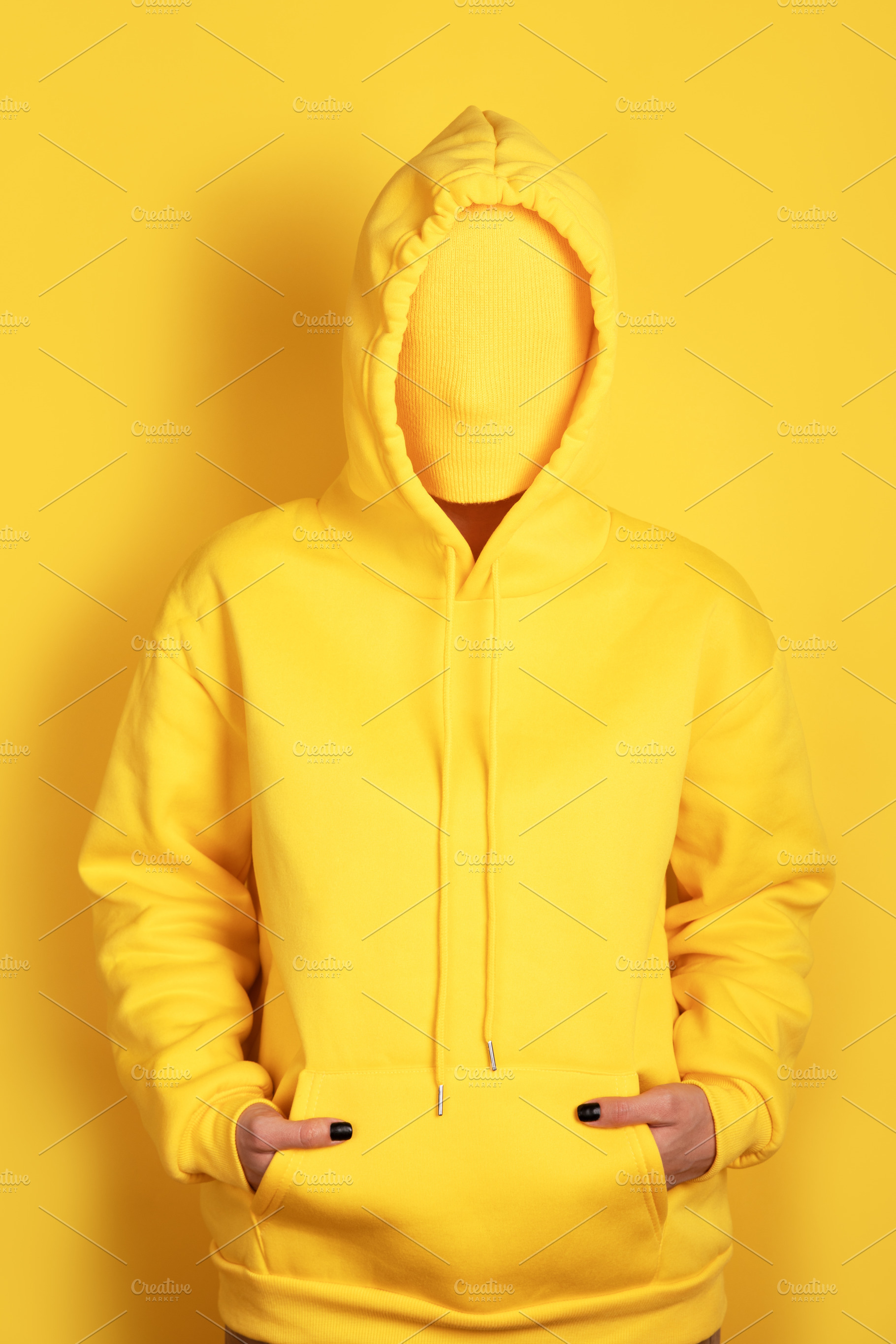 Faceless individual wearing a yellow hoodie against a yellow bac, a Person Photo by Ales Munt