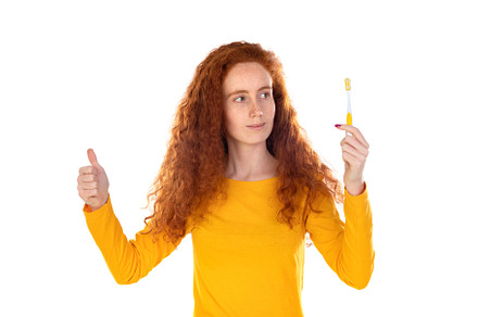Attractive smiling girl happily looking in camera brushing teeth, a Person Photo by José Manuel Gelpi