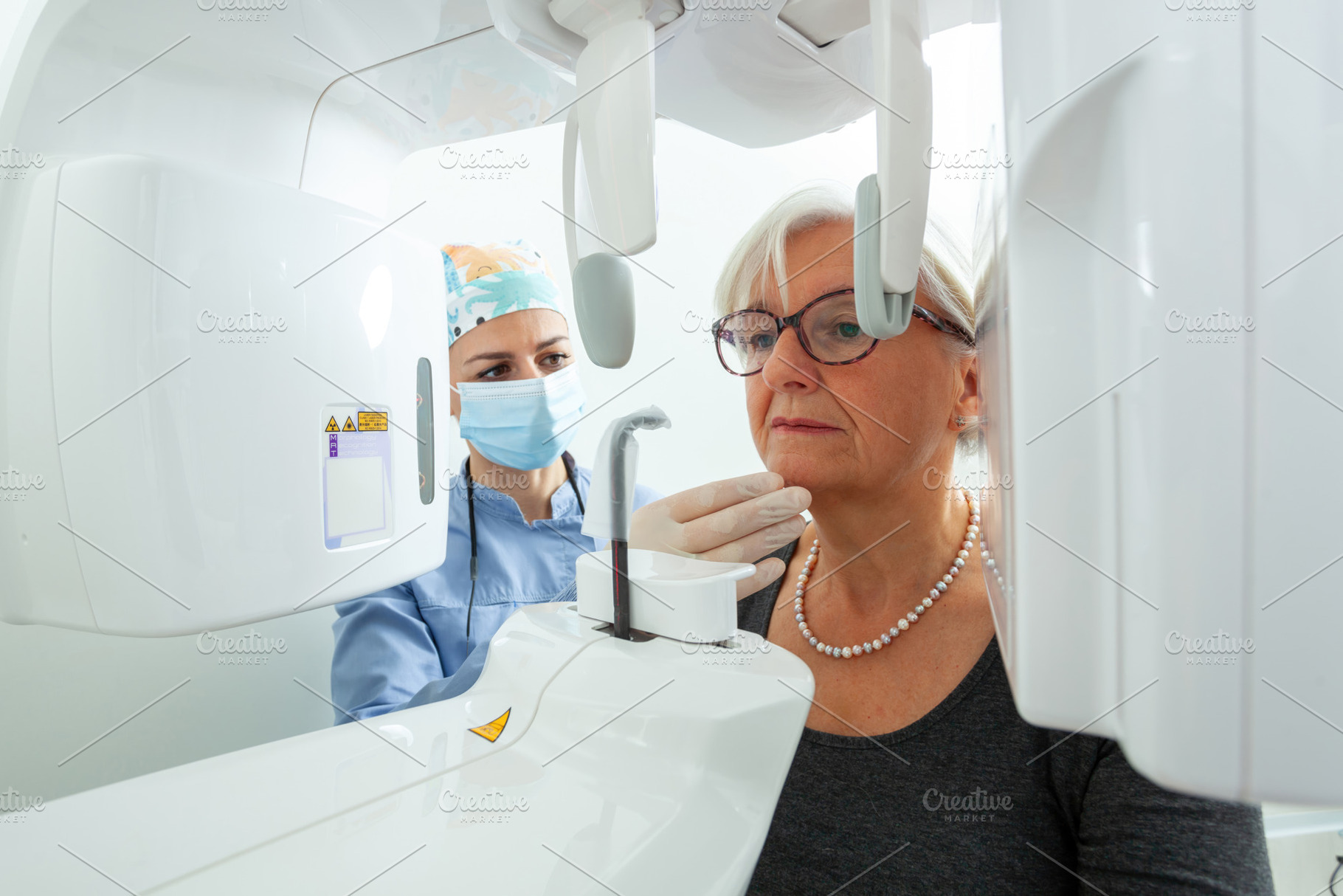 Dentist preparing elderly woman for dental x ray in clinic, a Photo by Antonio Gravante Market