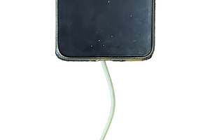 Mobile phone connected via USB cable to the stem of a plant leaf, a Technology Photo by DanFLCreativo