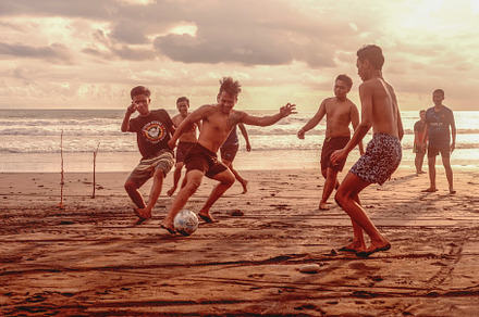 Men play football on the beach stock photo containing sunset and beach