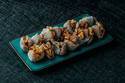 dried figs filled with walnuts on a green plate, a Photo by Nito