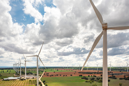 Wind turbine spinning over green farmland during daytime