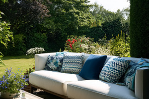 Outdoor patio sofa with blue accent pillows in a lush green summ, a Photo by Studio ANNA