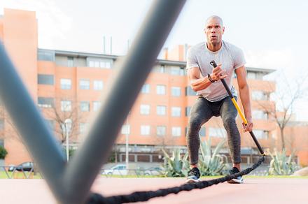 Low angle view of a sportsman exercising with an elastic gym stick in the park, a Sports & Recreation Photo by Iván Moreno STOCK PHOTO