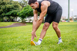 Athletic man stretching hamstrings on grass before outdoor workout, a Person Photo by etorres69