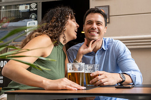 Happy Young Couple Enjoying Beer and Laughing Together at an Outdoor Cafe, a Person Photo by etorres69