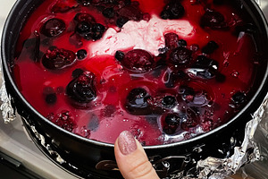 Hand holding a berry jelly dessert in the fridge for chilling, a Photo by AS photostudio