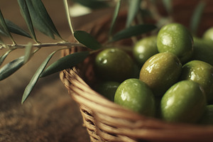 Green olives in a wicker basket with olive branch, symbolizing h, a Photo by Studio ANNA