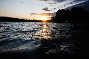 Sunset view over calm lake surrounded by silhouetted trees and serene reflectio, a Photo by AS photostudio