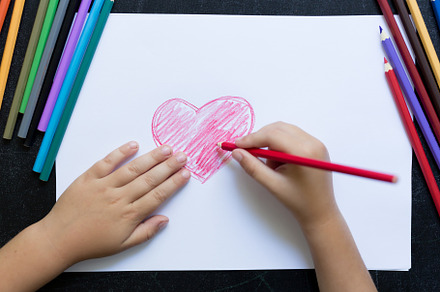 Kid's hands with pencil draws heart containing arm, art, and background