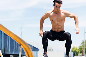 Shirtless athletic man jumping outdoors in city park, a Person Photo by RF Images