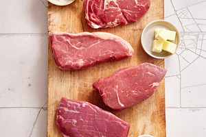 Raw rib-eye, roast beef, flank, and rump steak displayed on a wooden cutting bo, a Food & Drink Photo by Asya Nurullina