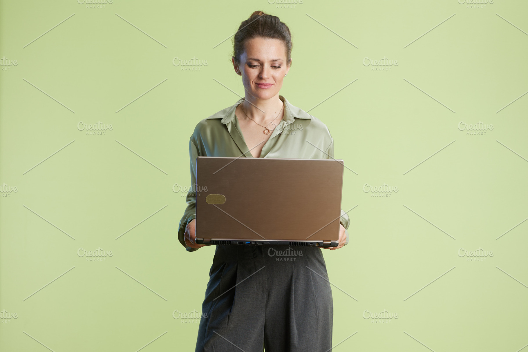 Woman in bright studio works on her laptop, focused, a Business Photo by Alliance Images