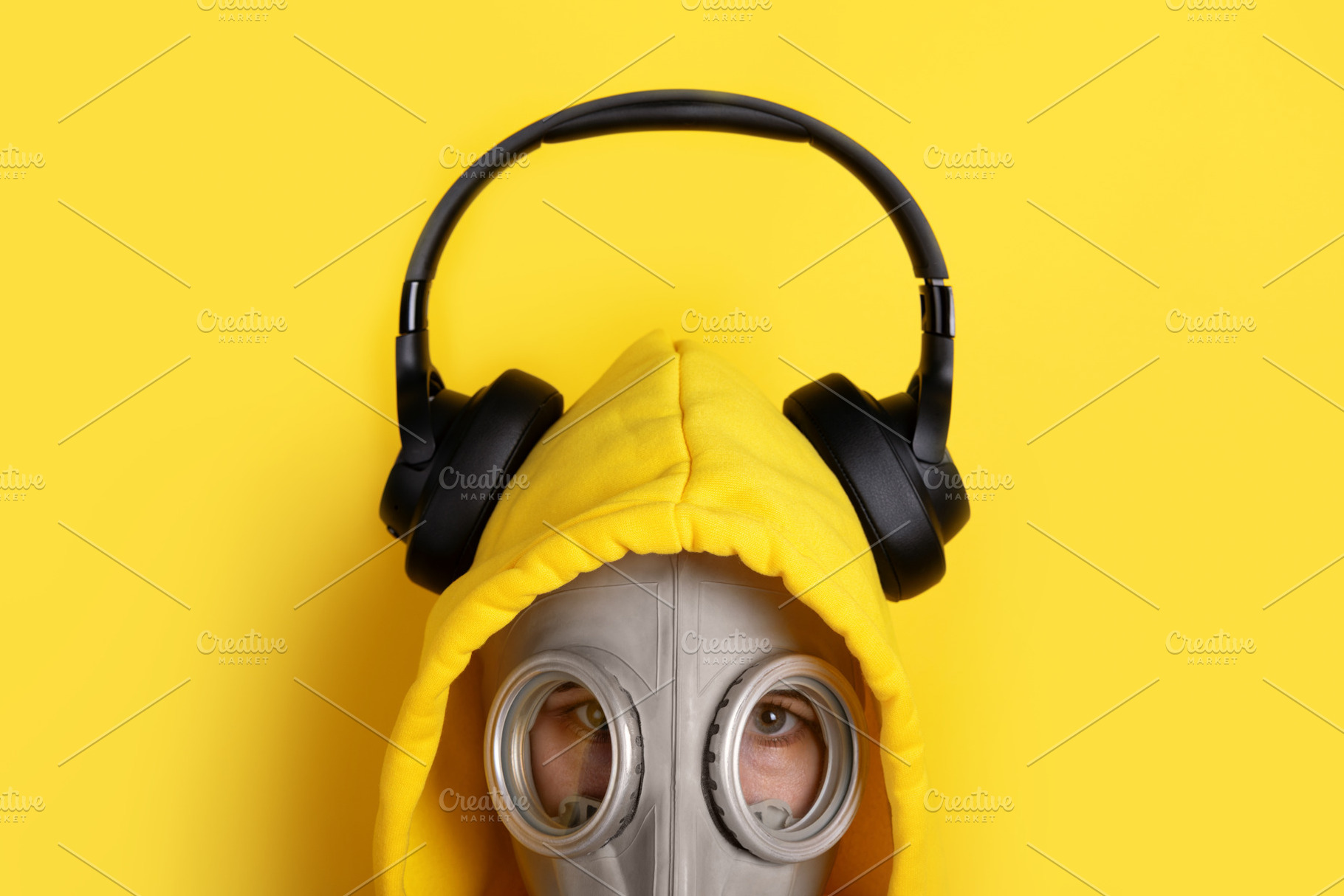 Person in a yellow hoodie and gas mask wearing black headphones,, a Person Photo by Ales Munt