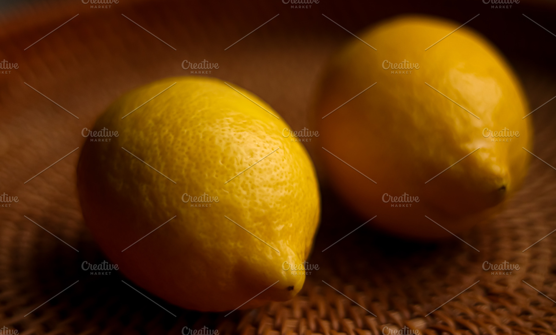 Fresh yellow lemons showing textured skin and bright color on a woven wicker ba, a Photo by Studio ANNA
