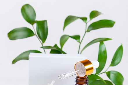 Brown glass pipette bottles with white podium, flowers and green leaves, vertic, a Beauty & Fashion Photo by iuliia_n