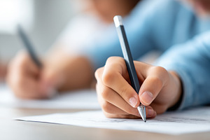 Close up of a student writing with, a School & Education Photo by MistyDay