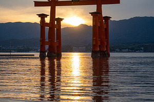 Famous red torii gate of Itsukushima shrine at sunset in Miyajim