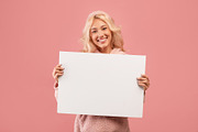 Joyful woman showing empty advertising placard, holding blank board for ad text, a Photo by Prostock-Studio (Thumbnail 2 of 2)