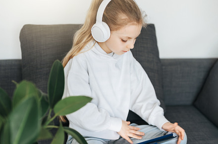 Little girl with headphones and tablet  at home, a School & Education Photo by Olena Rudo