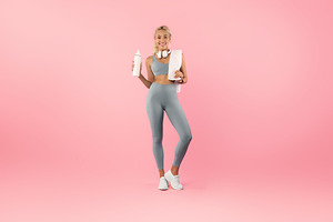 Sporty smiling woman posing at studio with water bottle, a Photo by Prostock-Studio