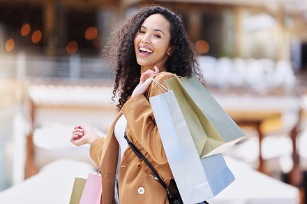 Shopping, happy and portrait of customer with bag after shopping spree buying retail fashion product on store discount. Sales, smile and young black woman at luxury shopping mall to purchase clothes, a Photo by Peopleimages.com
