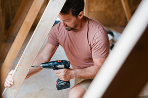 Father drilling into wooden beam, an Industrial Photo by HalfPoint