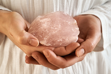 Hands holding a rose quartz stone
