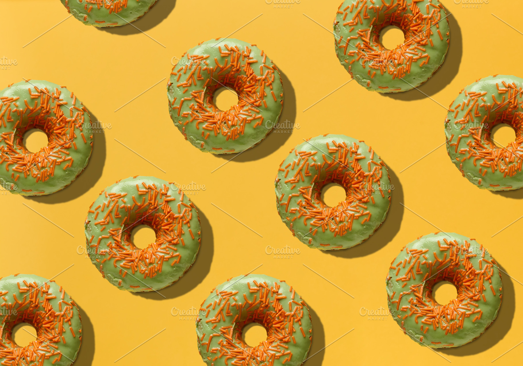 Green donuts with orange sugar sprinkles on yellow background, t, a Food & Drink Photo by ndanko