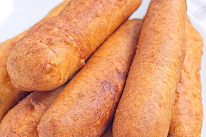 Stack of corn dogs on white plate, served with ketchup, vertical closeup, a Food & Drink Photo by iuliia_n