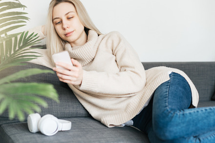 Happy young woman relaxing on comfortable couch, holding smartph, a Person Photo by Olena Rudo