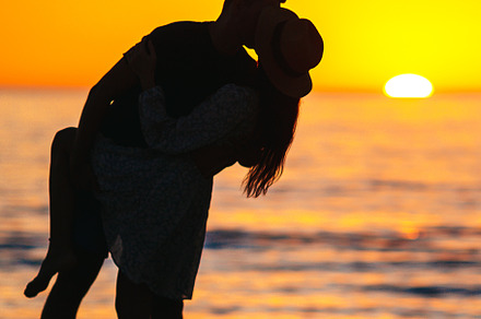 Romantic couple on the beach at colorful sunset on background, a Person Photo by travnikovstudio