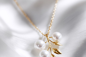 Pearl and gold leaf pendant necklace with a delicate chain on a, a Photo by Studio ANNA