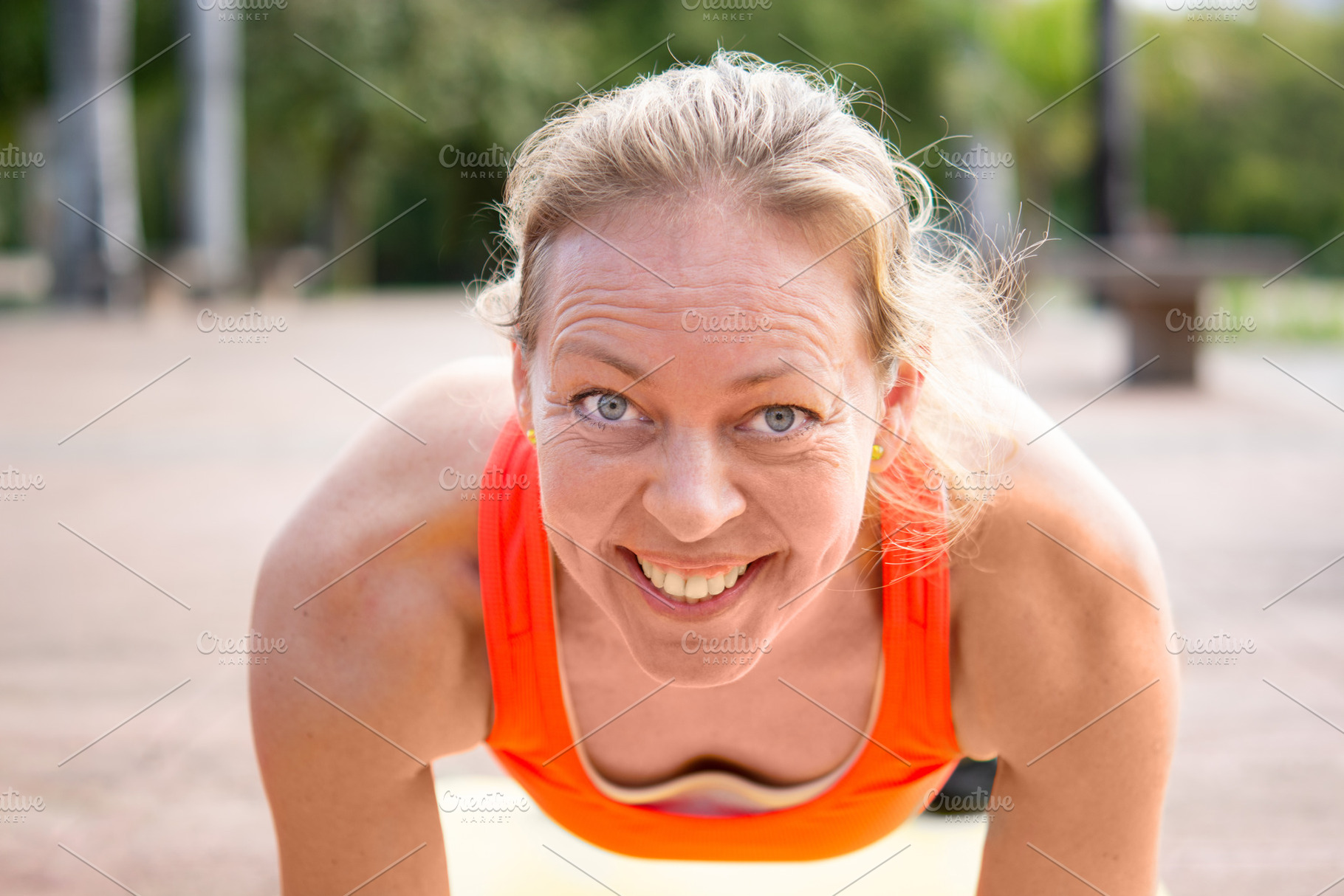 Smiling woman doing plank exercise looking at camera outdoors,, a Person Photo by etorres69