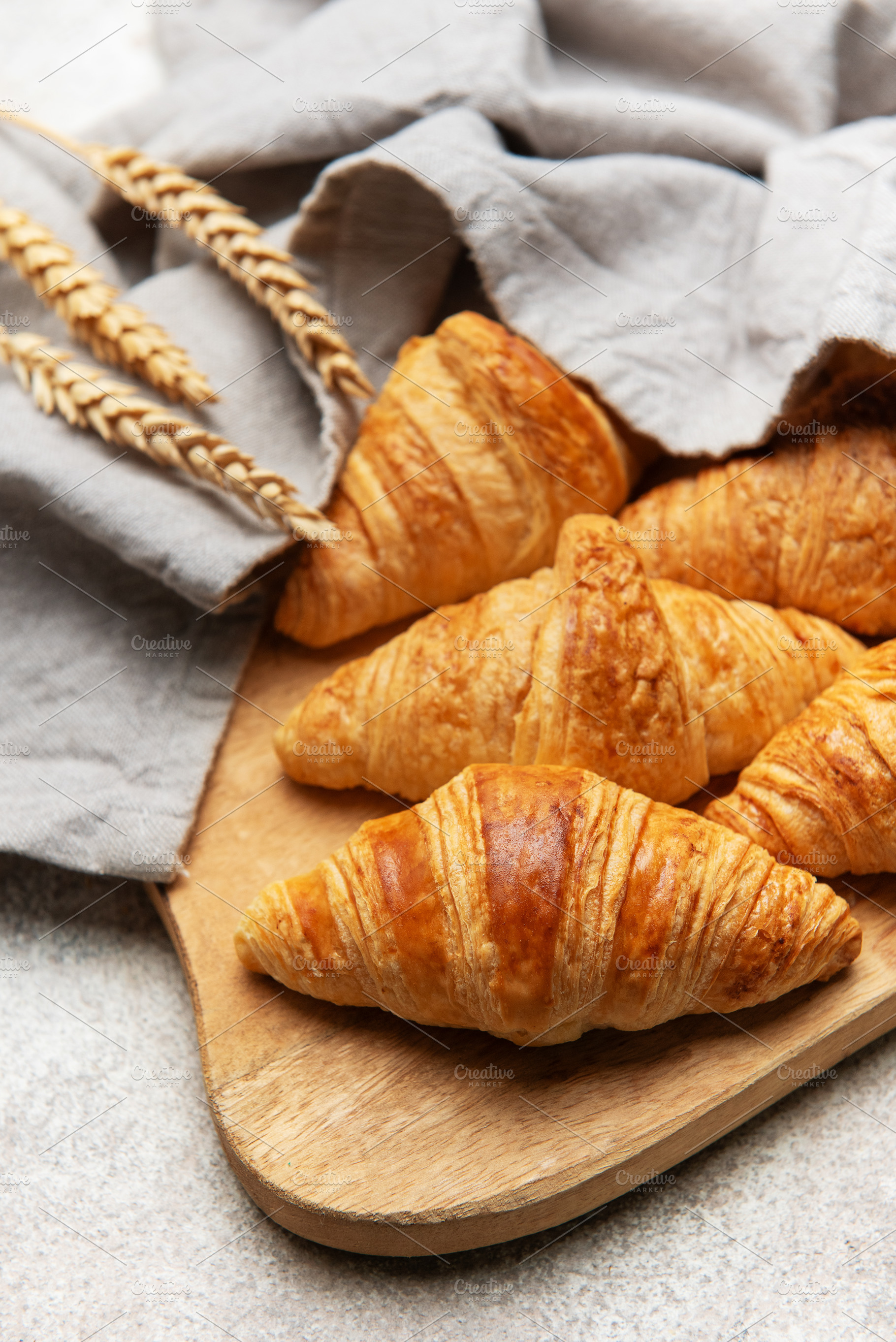 Freshly baked croissants resting on wooden cutting board with wh, a Food & Drink Photo by Olena Rudo