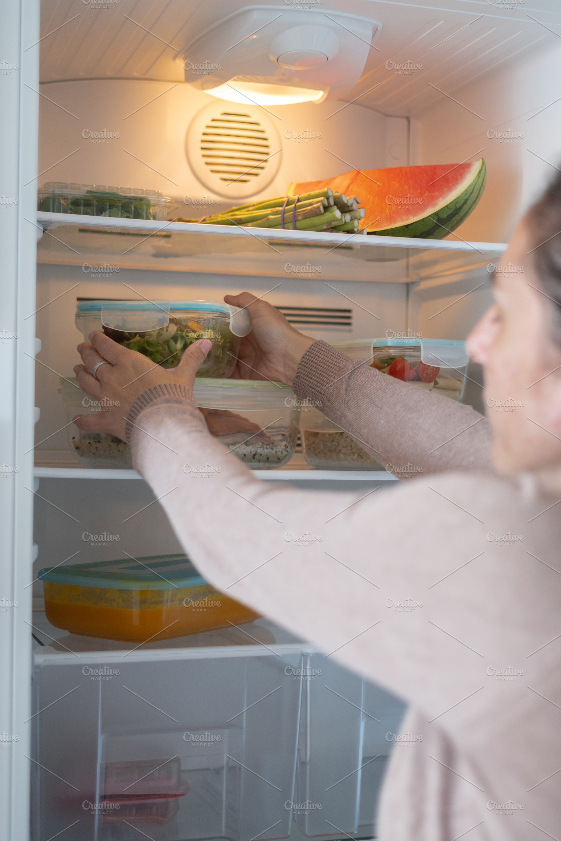 Woman Storing Healthy Meal Prep Containers in Refrigerator at Home, a Food & Drink Photo by etorres69