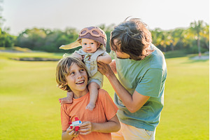 Father, son, and newborn on a meadow, a Person Photo by Elizaveta Galitskaya