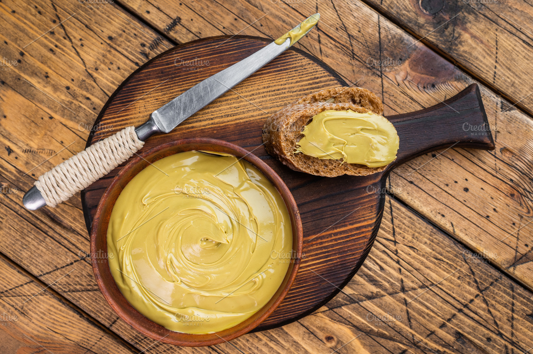 Sweet pistachio cream spread on bread with wooden bowl and knife, a Food & Drink Photo by composter-box@mail.ru