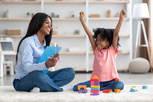 Emotional little girl raising hands up, having session with psychologist, a Photo by Prostock-Studio