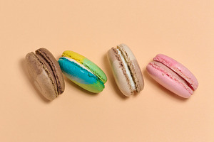 Multicolored macarons on a beige background, top view, a Food & Drink Photo by ndanko