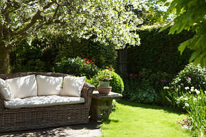 Wicker outdoor sofa inviting relaxation in a beautiful blooming, a Photo by Studio ANNA