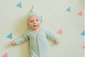 Adorable baby in a green hat lying, a Person Photo by Elizaveta Galitskaya