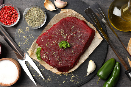 Concept of cooking with raw beef steak on dark wooden background, a Food & Drink Photo by AtlasStudio PRO