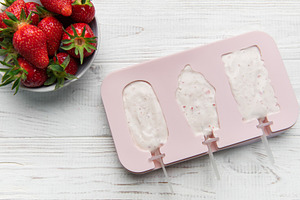 Preparing homemade strawberry yogurt popsicles on wooden backgro, a Food & Drink Photo by Olena Rudo