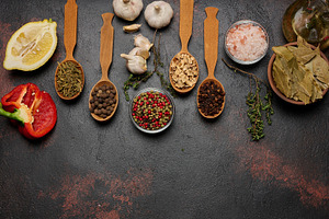 Spices on a dark background in wooden spoons: pepper, cloves, gi, a Food & Drink Photo by ndanko