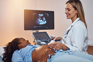 Pregnant black woman in a medical room getting an abdominal ultr, a Health & Medical Photo by DanFLCreativo