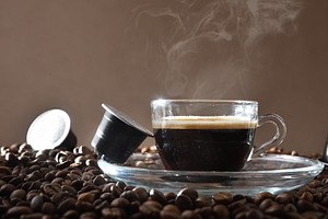 Espresso cup on ground coffee with capsules around front view, a Food & Drink Photo by Davizro's Market